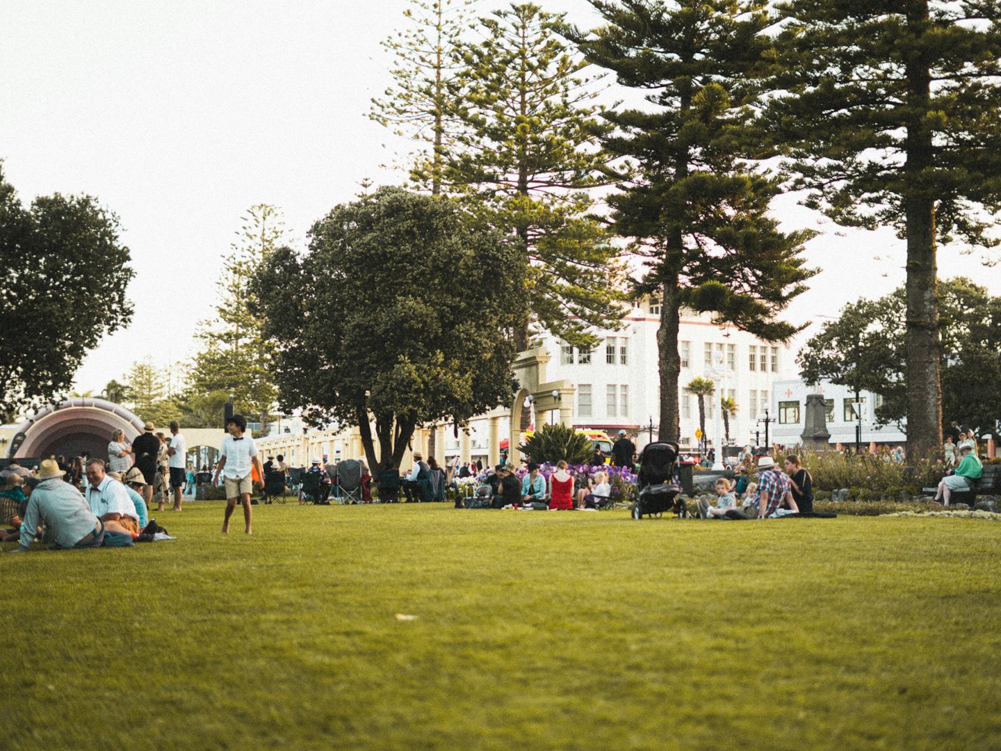Des gens se détendent et se promènent sur l'herbe d'un parc urbain.